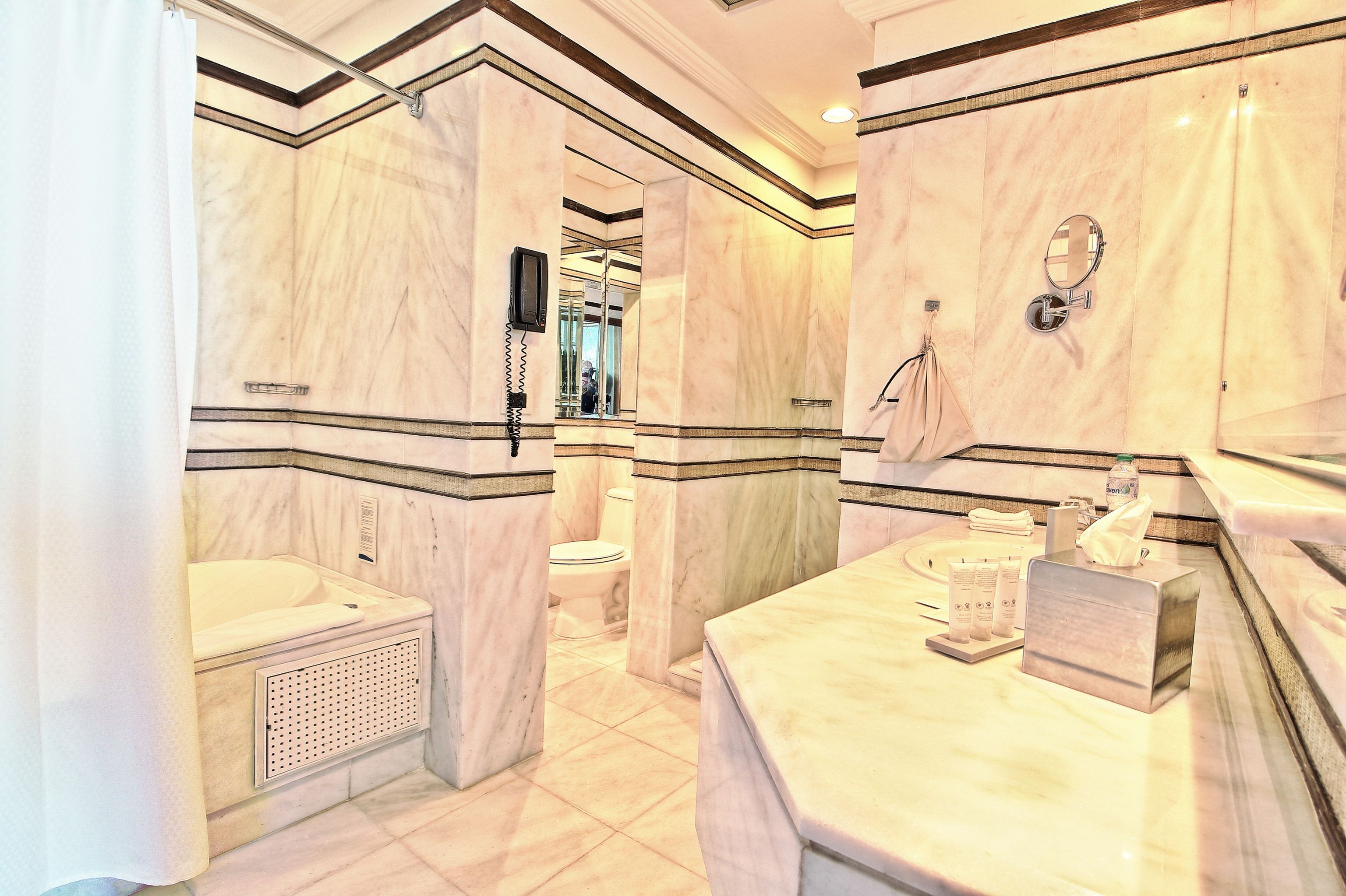 A marble bathroom with a bathtub, toilet, and vanity.
