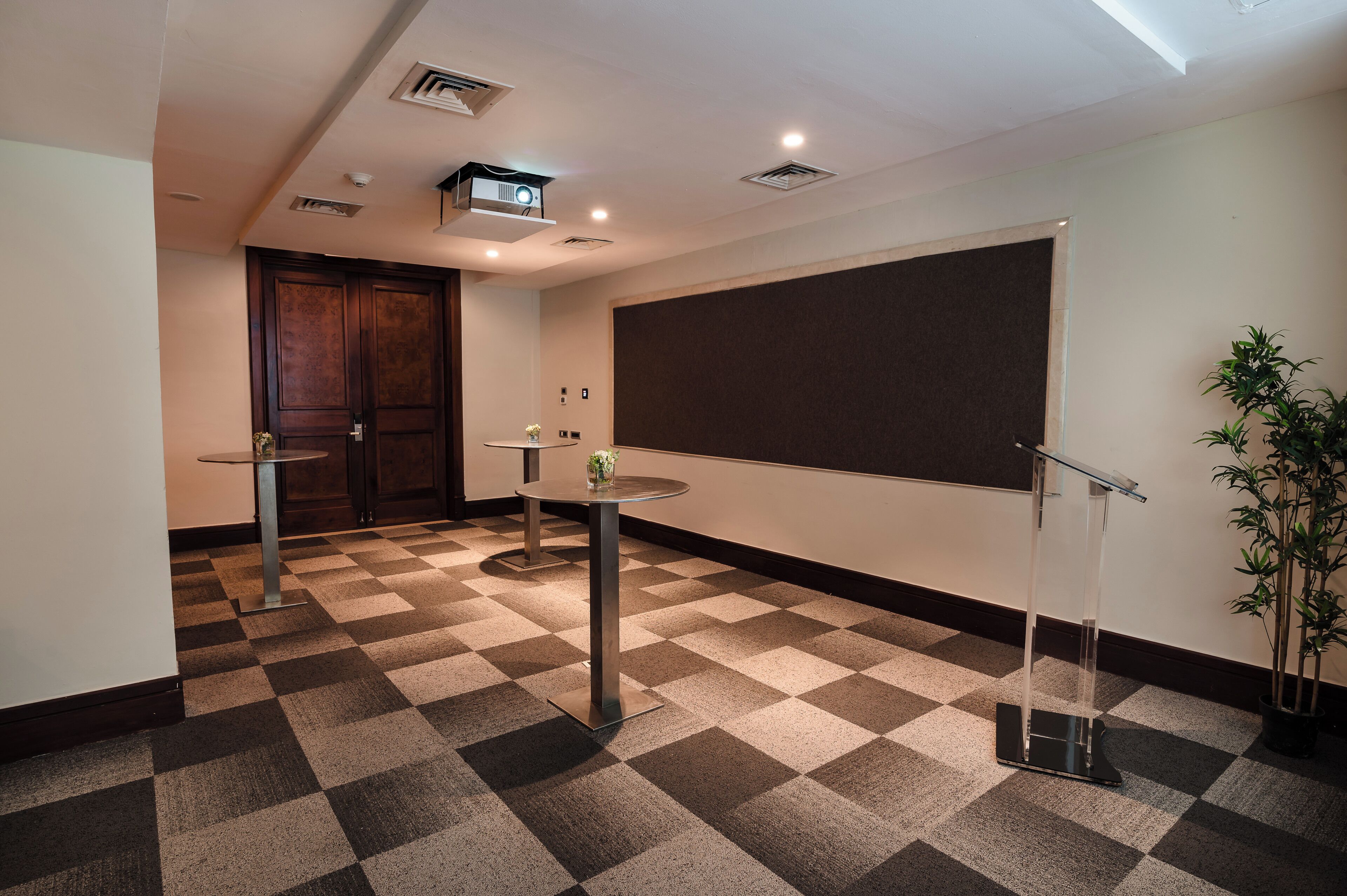 A conference room with a checkered floor, a projector, a screen, and a podium.