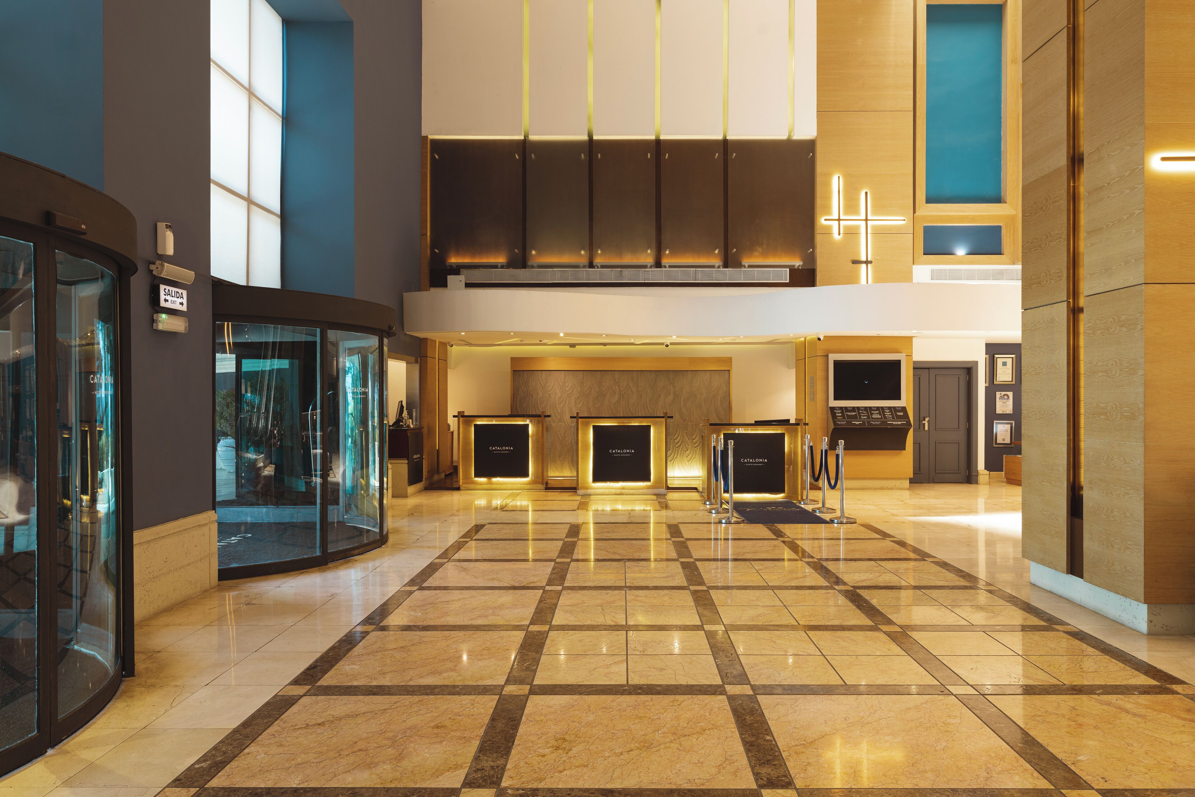 A spacious lobby with a checkered floor, glass walls, and a reception area with a counter.