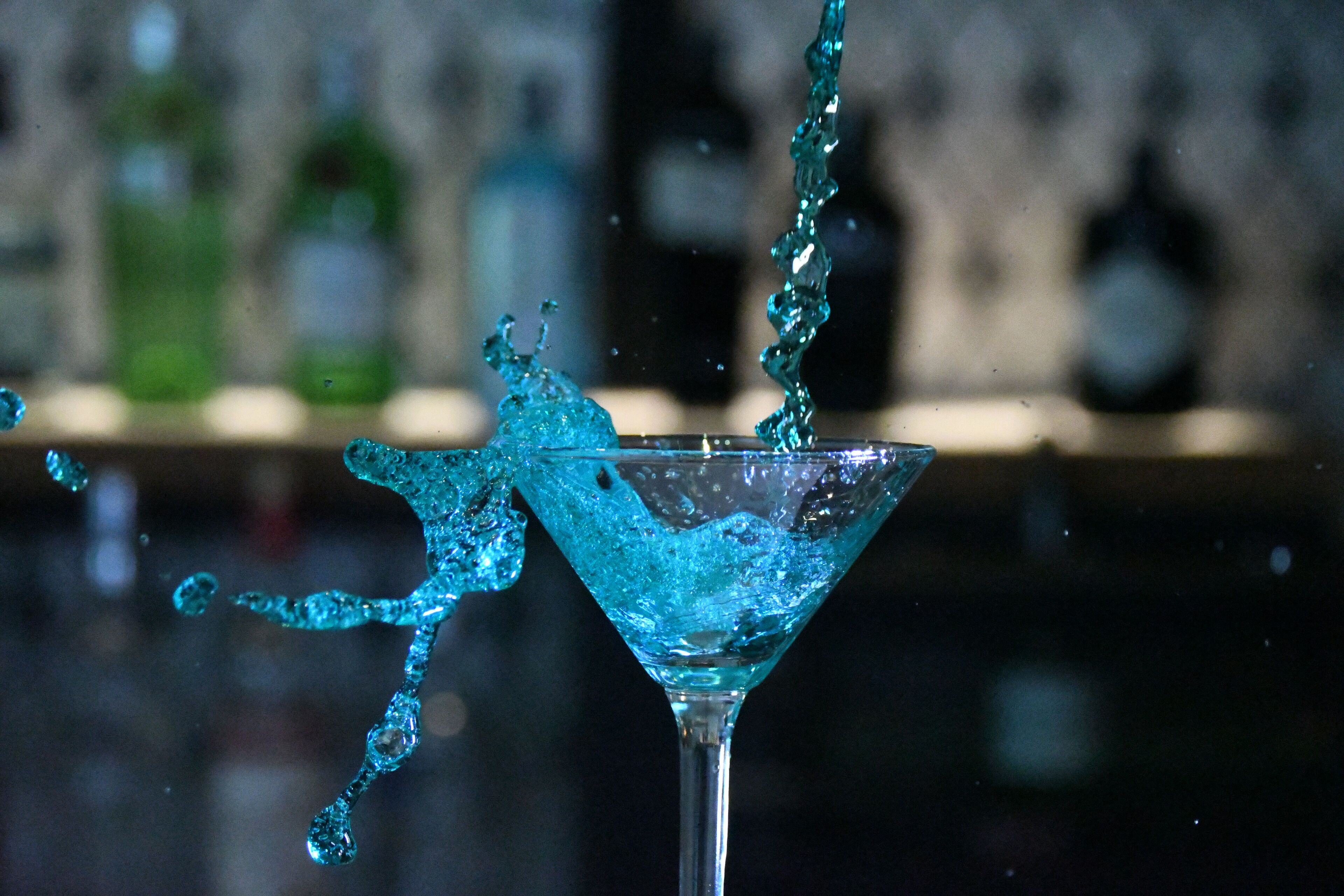 A martini glass with a splash of blue liquid.