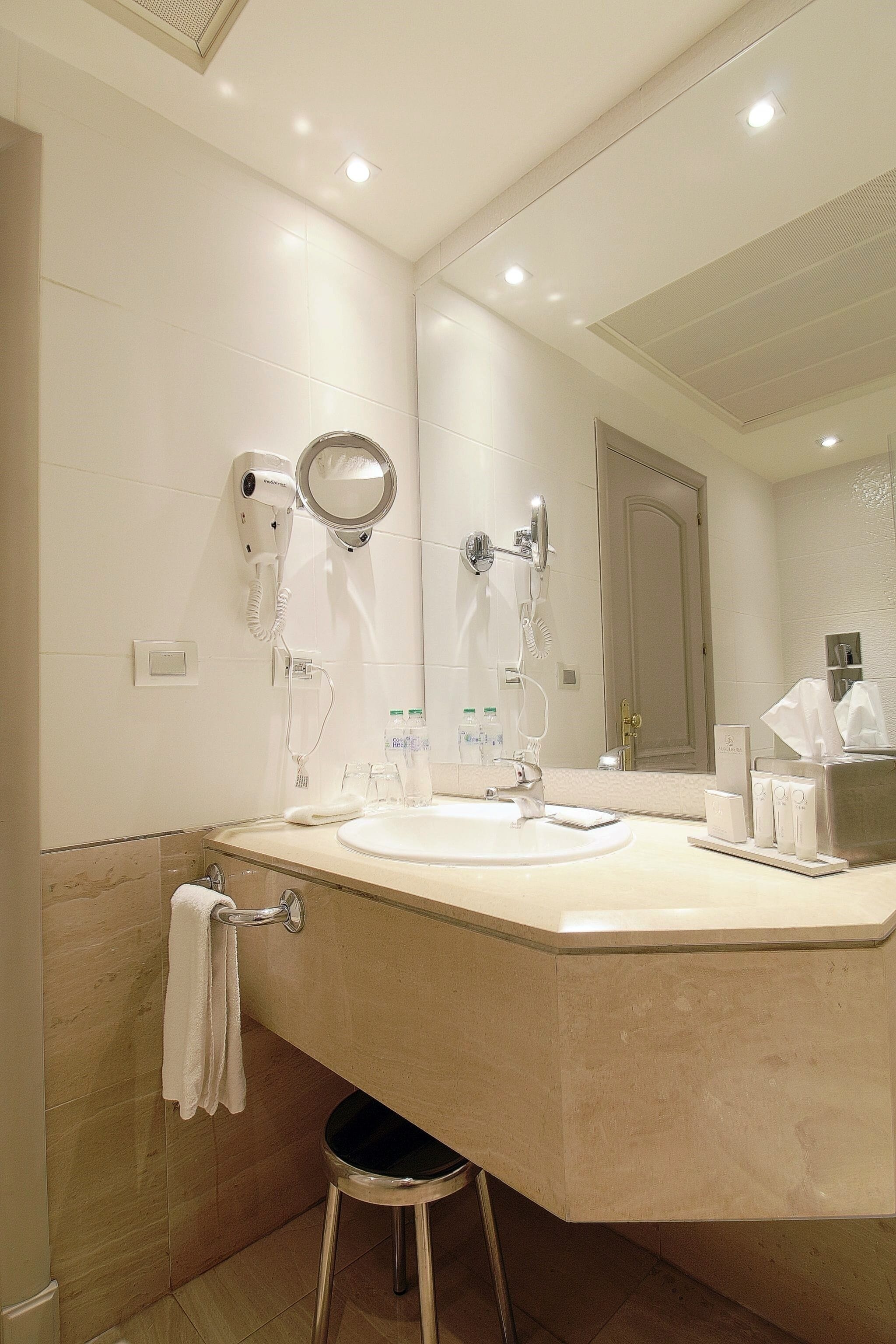 A modern bathroom with a large mirror, a hairdryer, and a sink.