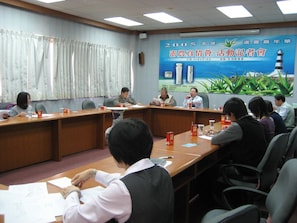 A conference room with a long table, chairs, and a banner on the wall. - Penghu Farmers Association Resort (Magong)