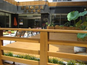A restaurant with a wooden fence, outdoor seating, and potted plants. - Penghu Farmers Association Resort (Magong)