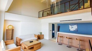 Un interior moderno con zona de estar tipo loft, una barra de comedor y una escalera que lleva a un nivel superior.