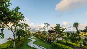 Un jardín con un sendero de piedra, un pabellón de madera y abundante vegetación.