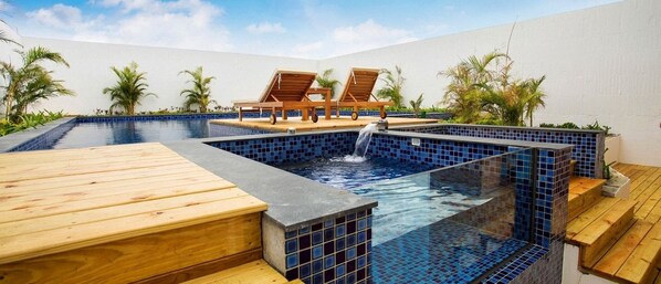 A swimming pool with a wooden deck and lounge chairs. - Sheng Tu Villa (Hengchun)
