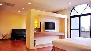 A hotel room with a bed, a television mounted on a wall, a small table, and a window. - Kenting Culture Resort (Hengchun)