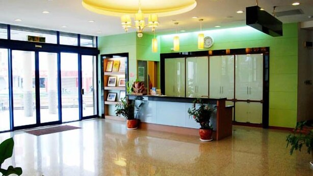 A reception area with a glass door entrance, a reception desk, and potted plants. - Kenting Culture Resort (Hengchun)