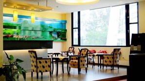 A dining area with a large window, a painting of a landscape, and patterned chairs. - Kenting Culture Resort (Hengchun)