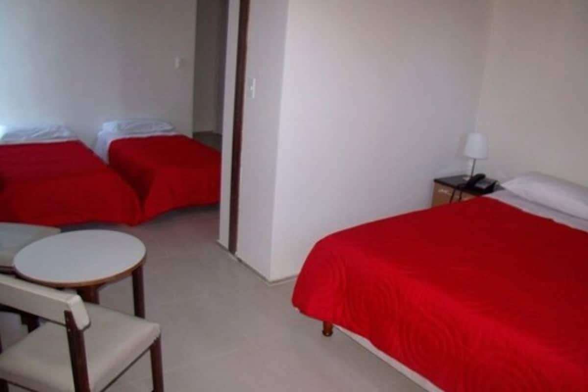 A hotel room with two single beds, a small round table, and a chair.