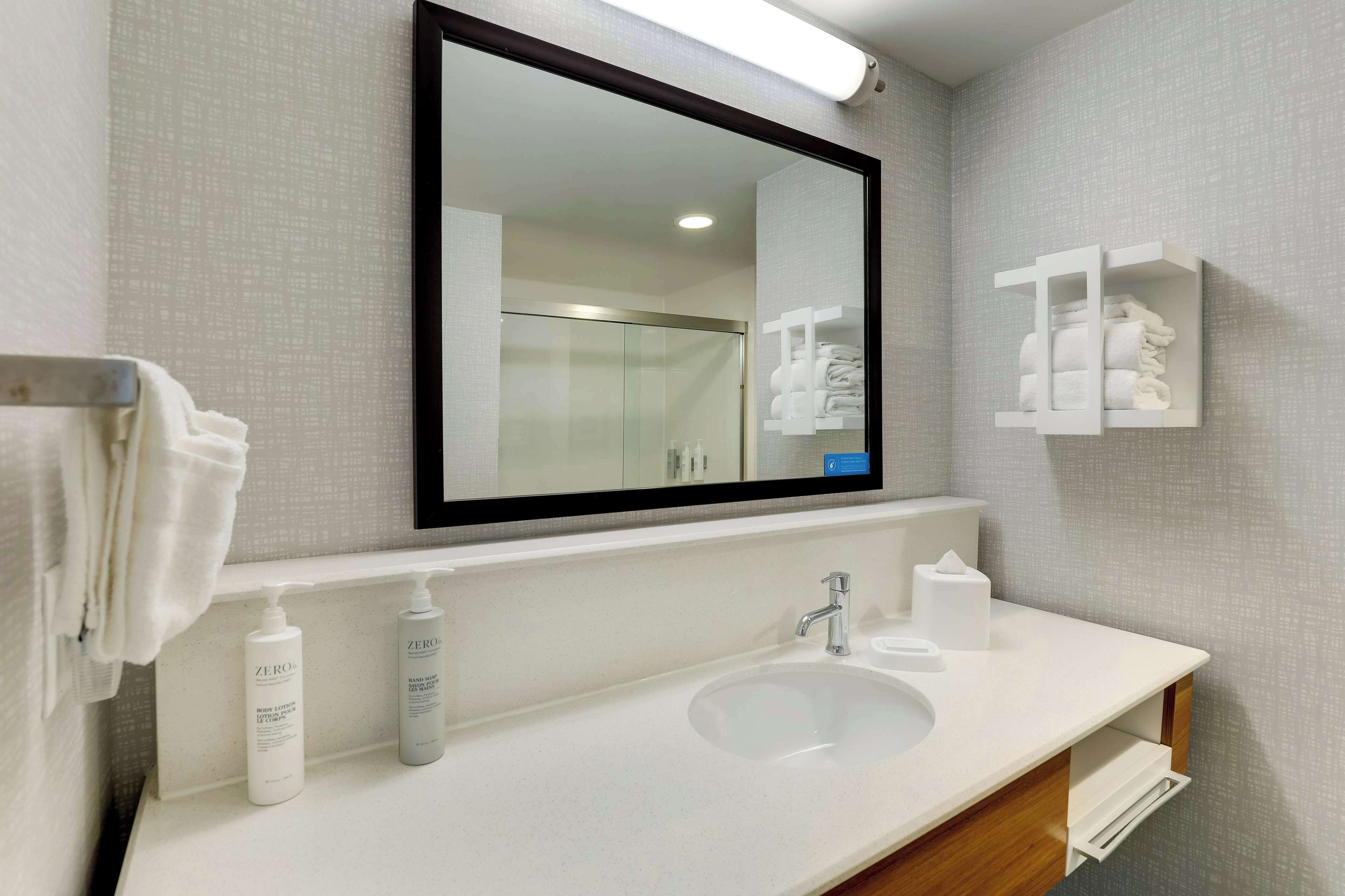 A bathroom with a white sink, a mirror, and a towel rack.