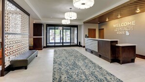 A reception area with a 'Welcome to the Peach State' sign, a reception desk, and a patterned rug. - Hampton Inn & Suites Rome (Rome)