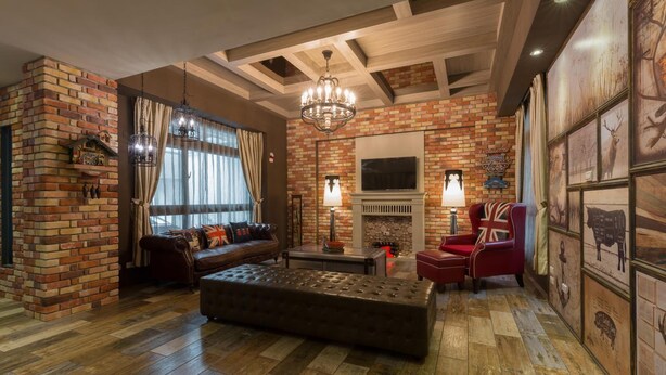 A cozy living room with a brick fireplace, a large leather sofa, a red armchair, and a wooden floor. - Ali Ba Ba B&B I (Hualien City)