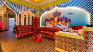 A vibrant hotel lobby with a red sofa, a red table, and a colorful mural on the wall. - Ali Ba Ba B&B I (Hualien City)