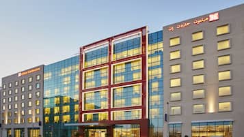A modern hotel with a glass facade, multiple floors, and a prominent entrance.