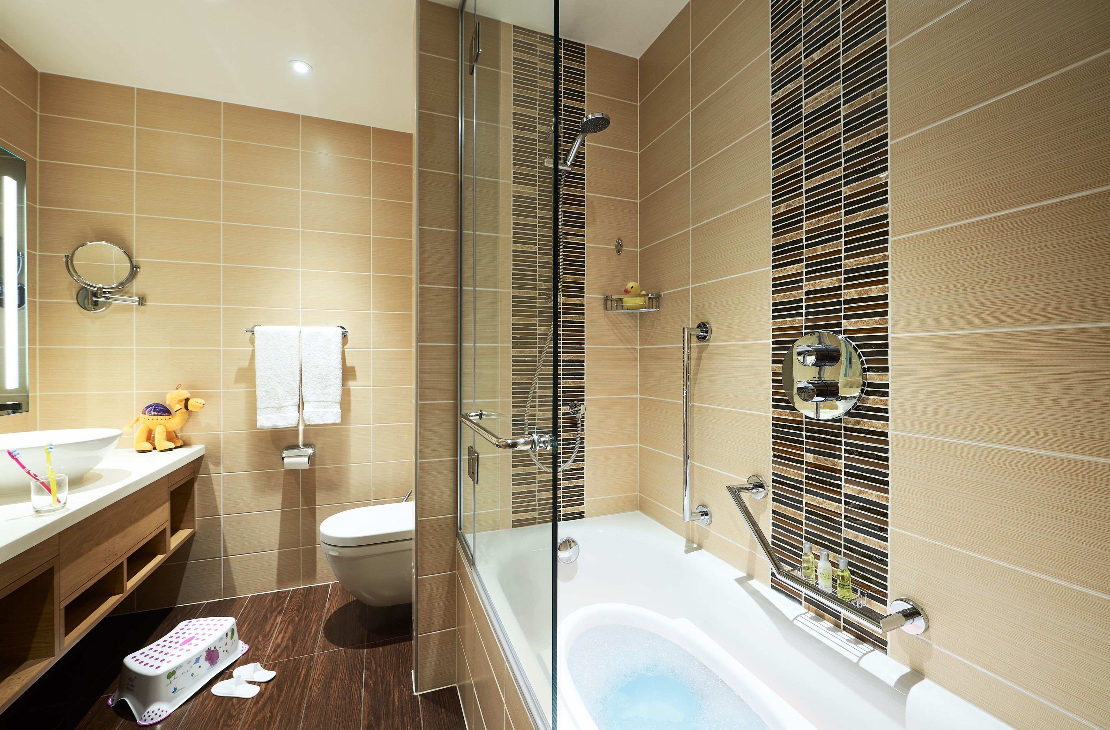 A modern bathroom with a glass shower enclosure, a bathtub, and a toilet.