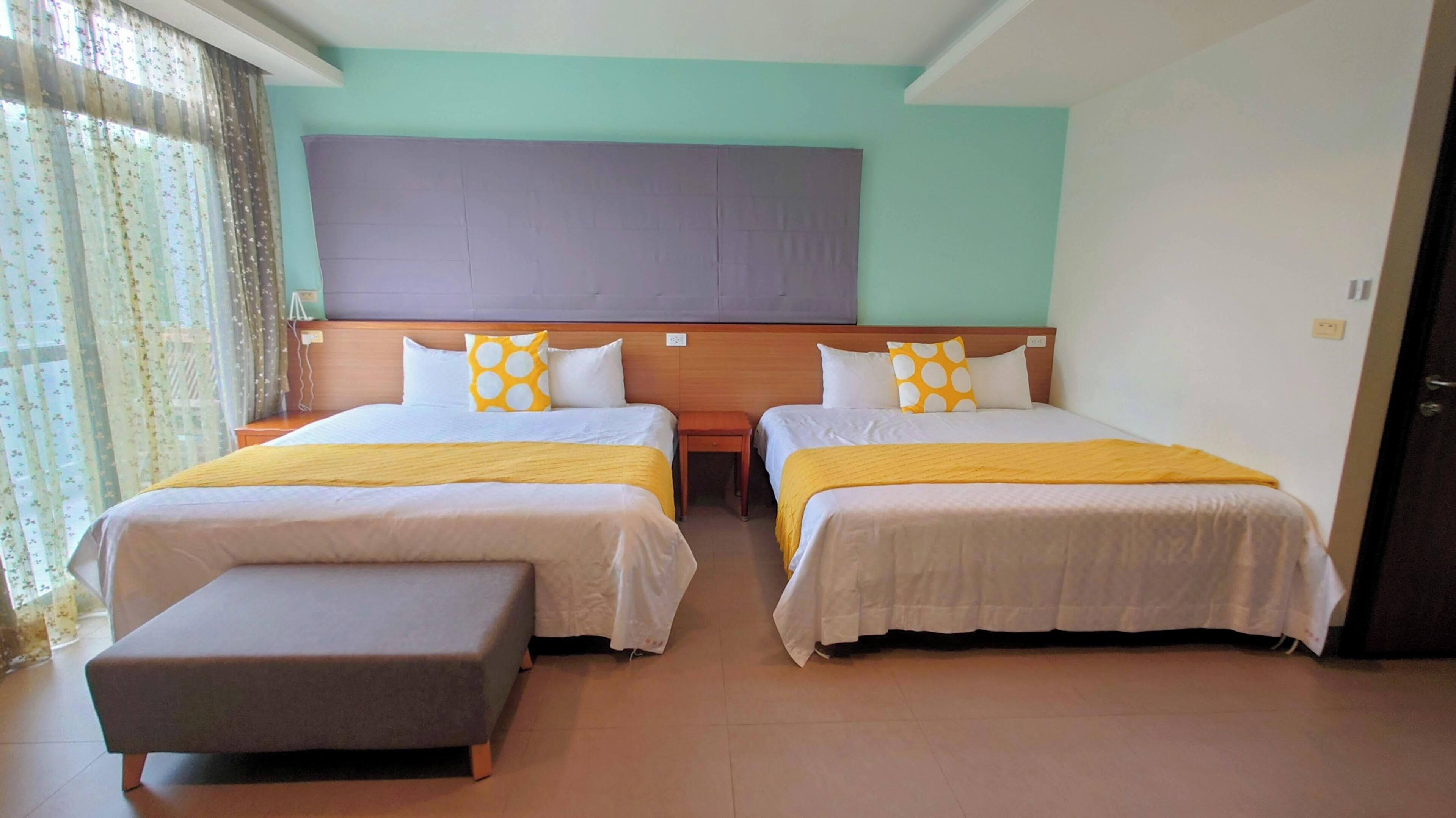 Habitación de hotel con dos camas, un cabecero de madera y un banco.