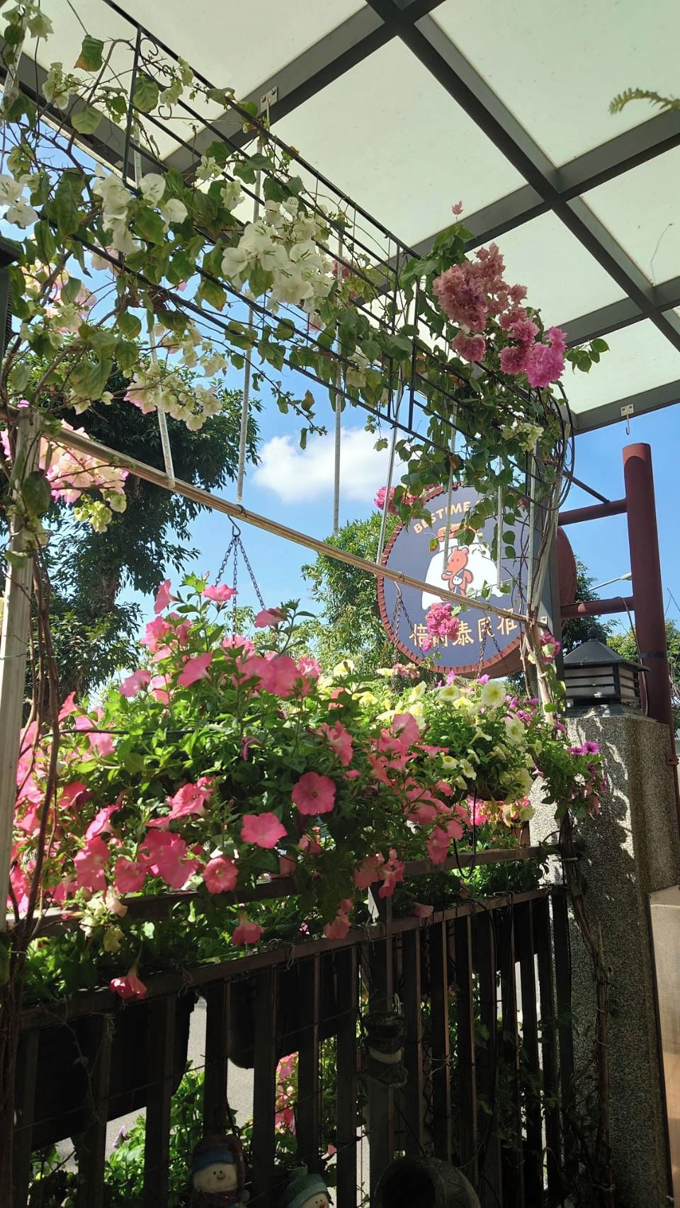 Un invernadero con plantas colgantes y un cartel con caracteres japoneses.