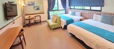 A hotel room with a TV, a desk, a sofa, two beds, and a window with curtains.