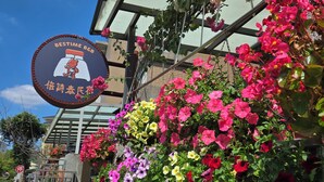 A building with a sign reading "BESTIME BBQ" and a variety of colorful flowers. - Bestime BnB (Jiji)