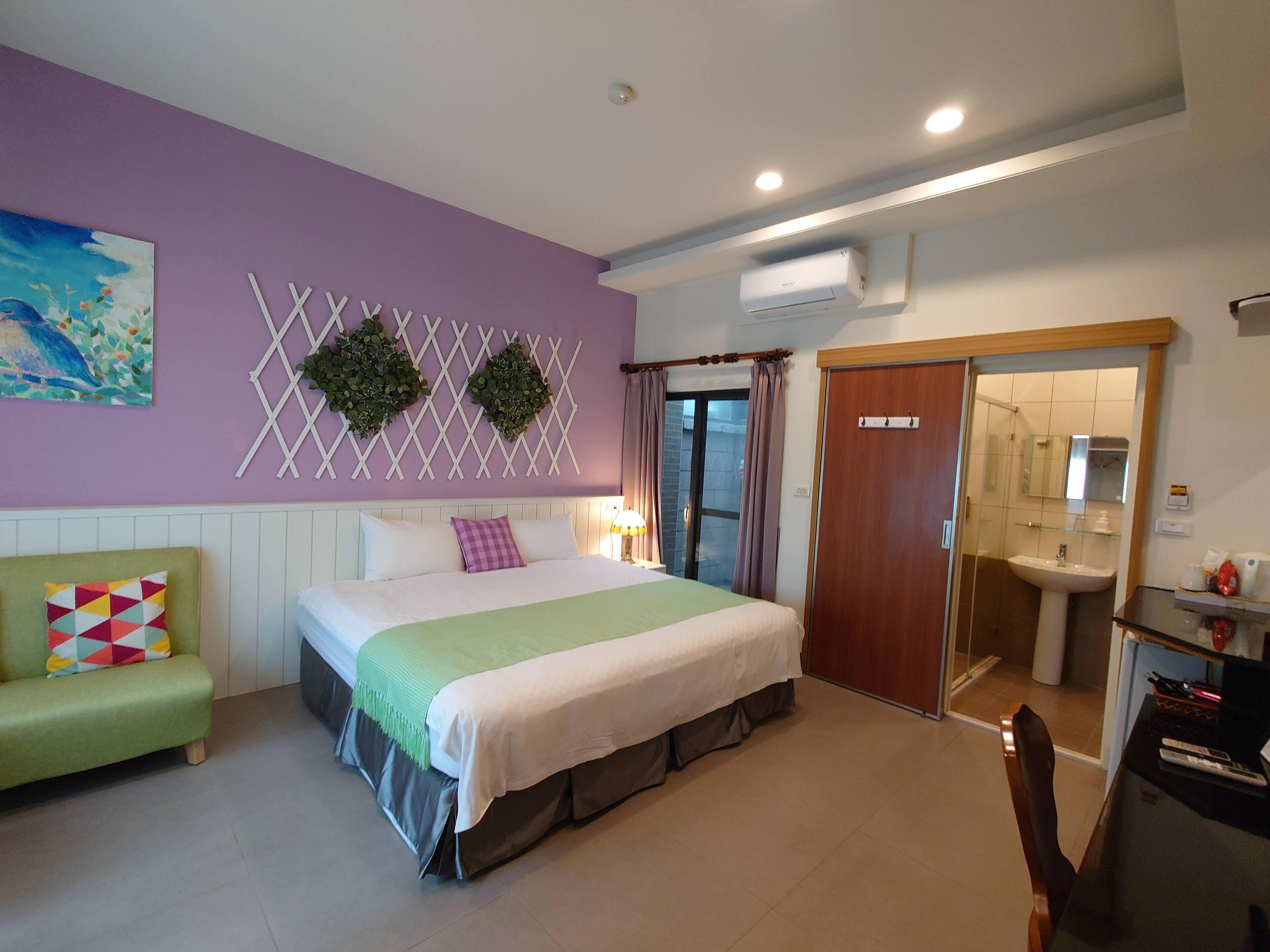 Une chambre à coucher avec un lit, un canapé vert, une salle de bain avec un lavabo et une porte donnant sur une autre pièce.