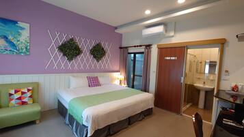 Une chambre à coucher avec un lit, un canapé vert, une salle de bain avec un lavabo et une porte donnant sur une autre pièce.