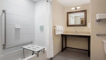 A modern bathroom with a walk-in shower, grab bars, a vanity with a mirror, and a toilet.