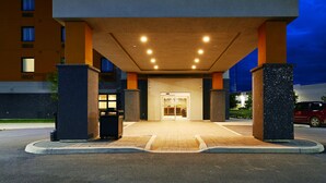 A modern hotel entrance with a covered walkway, a reception desk, and a parking area. - Quality Inn & Suites (Kingston)