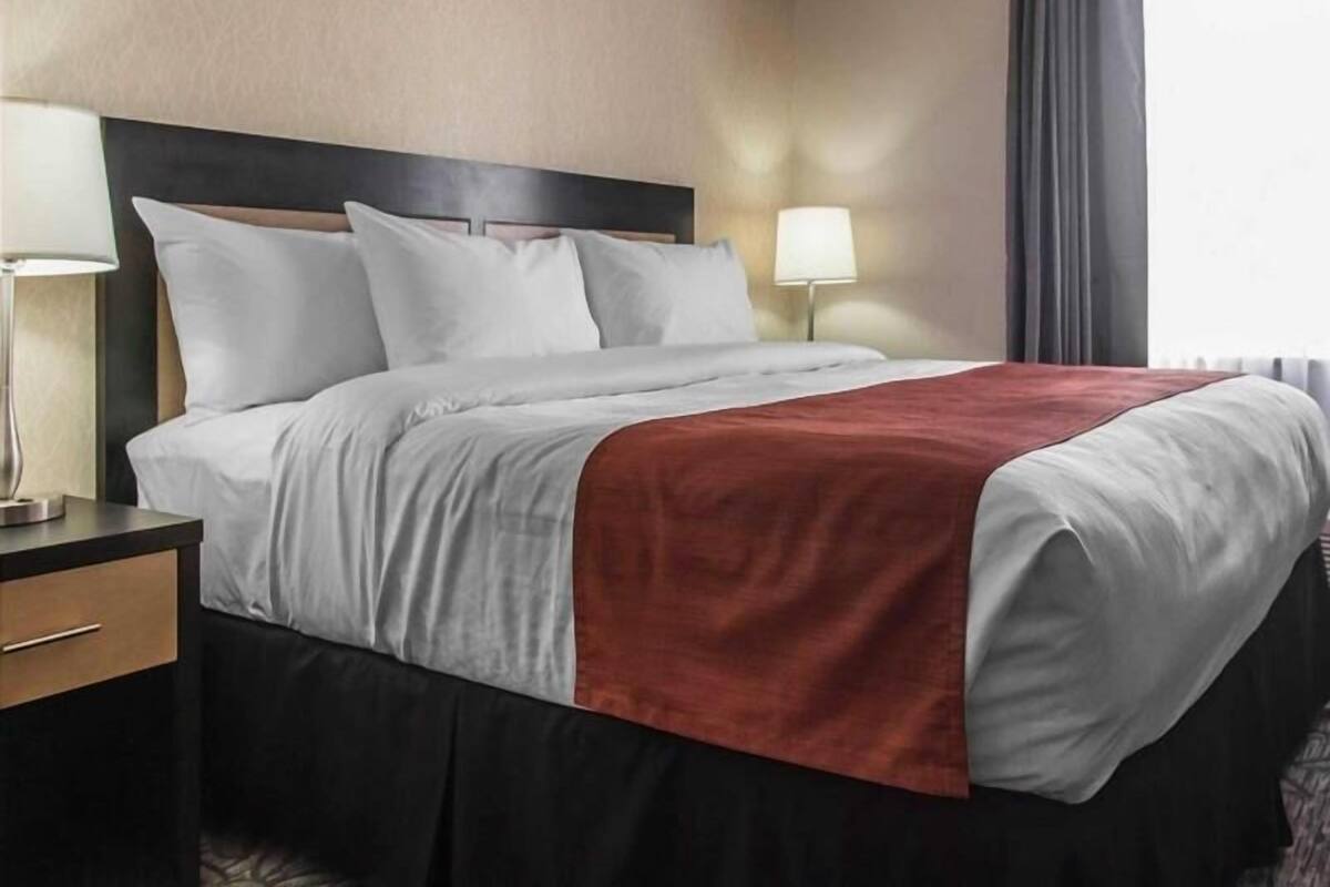 A hotel room with a bed, bedside tables, a lamp, and a window with curtains.