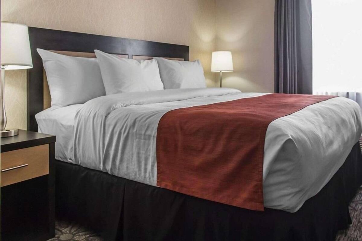 A hotel room with a bed, bedside tables, and a window with curtains.