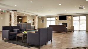 A spacious lobby with a reception desk, seating area, and a fireplace. - Quality Inn & Suites (Kingston)