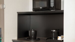 A kitchenette with a microwave, a coffee maker, and a coffee cup on a counter. - Quality Inn & Suites (Kingston)