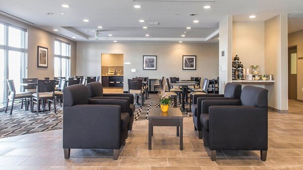 A spacious lobby with multiple seating areas, a central coffee table, and a kitchenette in the background. - Quality Inn & Suites (Kingston)
