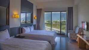 A hotel room with two beds, a balcony with a view, and a seating area with a TV. - Flowers Bed and Breakfast (Ji'an)