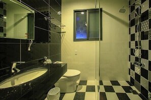 A bathroom with a black and white checkered floor, a white toilet, a black sink, and a shower with a glass door. - Flowers Bed and Breakfast (Ji'an)