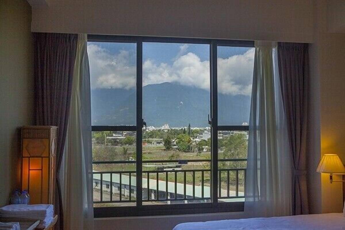 A hotel room with a large window offering a view of a mountain and a cityscape.