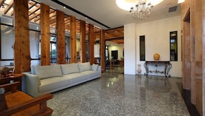 A spacious living area with a light-colored sofa, wooden beams, a chandelier, and a polished floor. - Flowers Bed and Breakfast (Ji'an)
