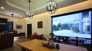 A modern hotel lobby with wooden furniture, a large screen displaying an outdoor view, and two unique chandeliers. - Flowers Bed and Breakfast (Ji'an)