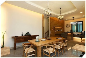 A modern kitchen with a wooden dining table, chairs, and pendant lights. - Flowers Bed and Breakfast (Ji'an)
