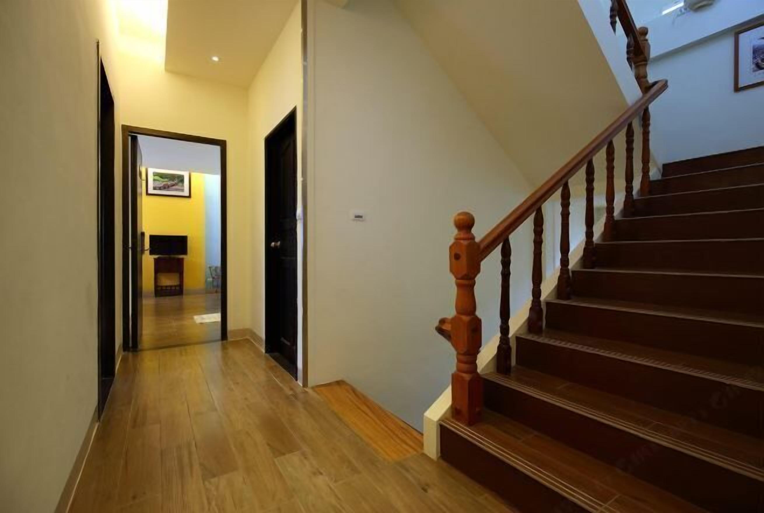 A wooden staircase with a handrail leading to a landing. A hallway with wooden flooring extends from the staircase.