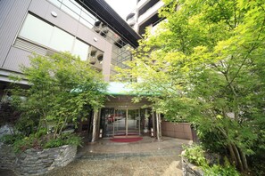 A hotel entrance with a red carpet, stone wall, and glass doors.