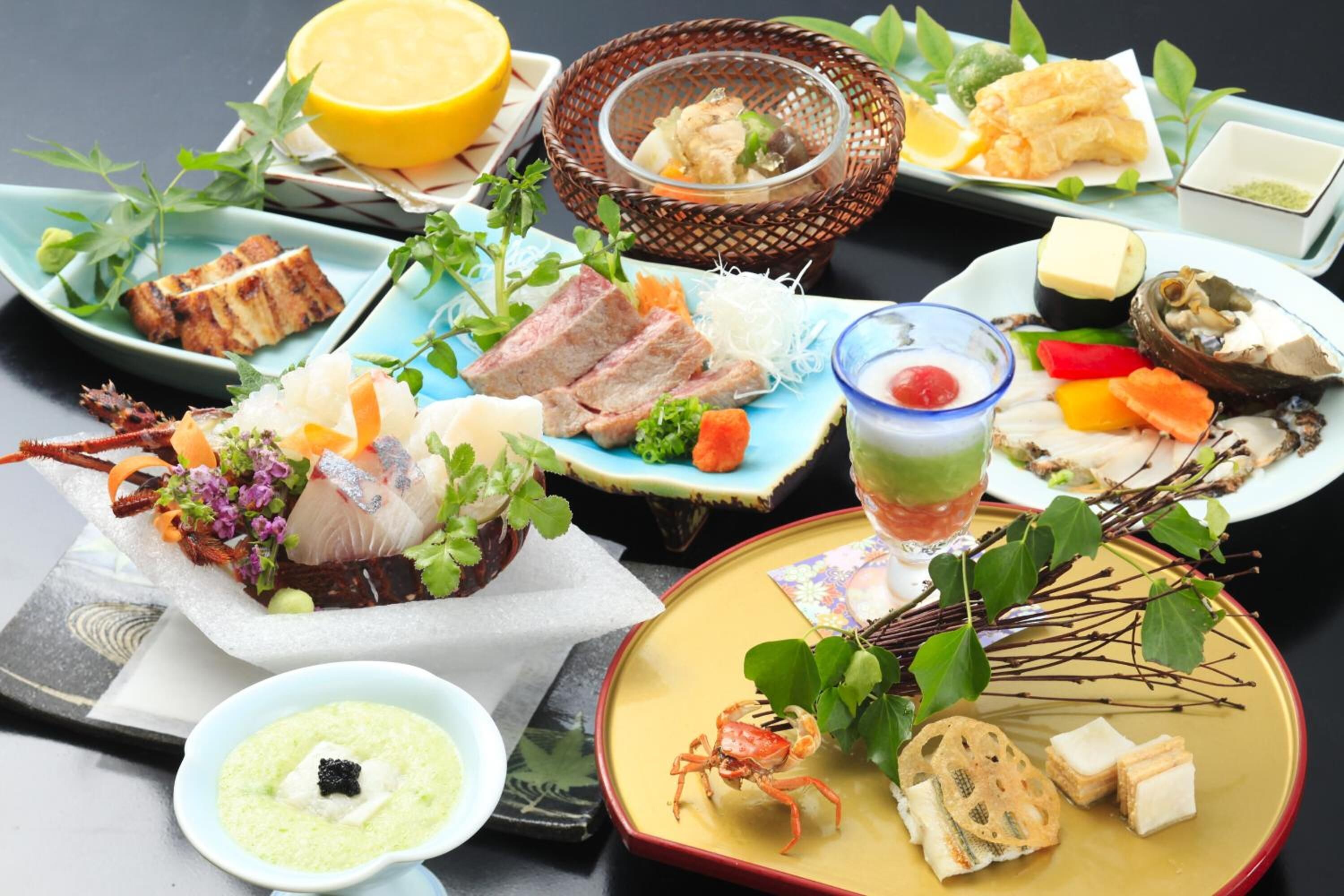 Diversos platos que incluyen mariscos, carne a la parrilla y verduras, presentados sobre una mesa con un vaso de bebida y elementos decorativos como hojas y flores.