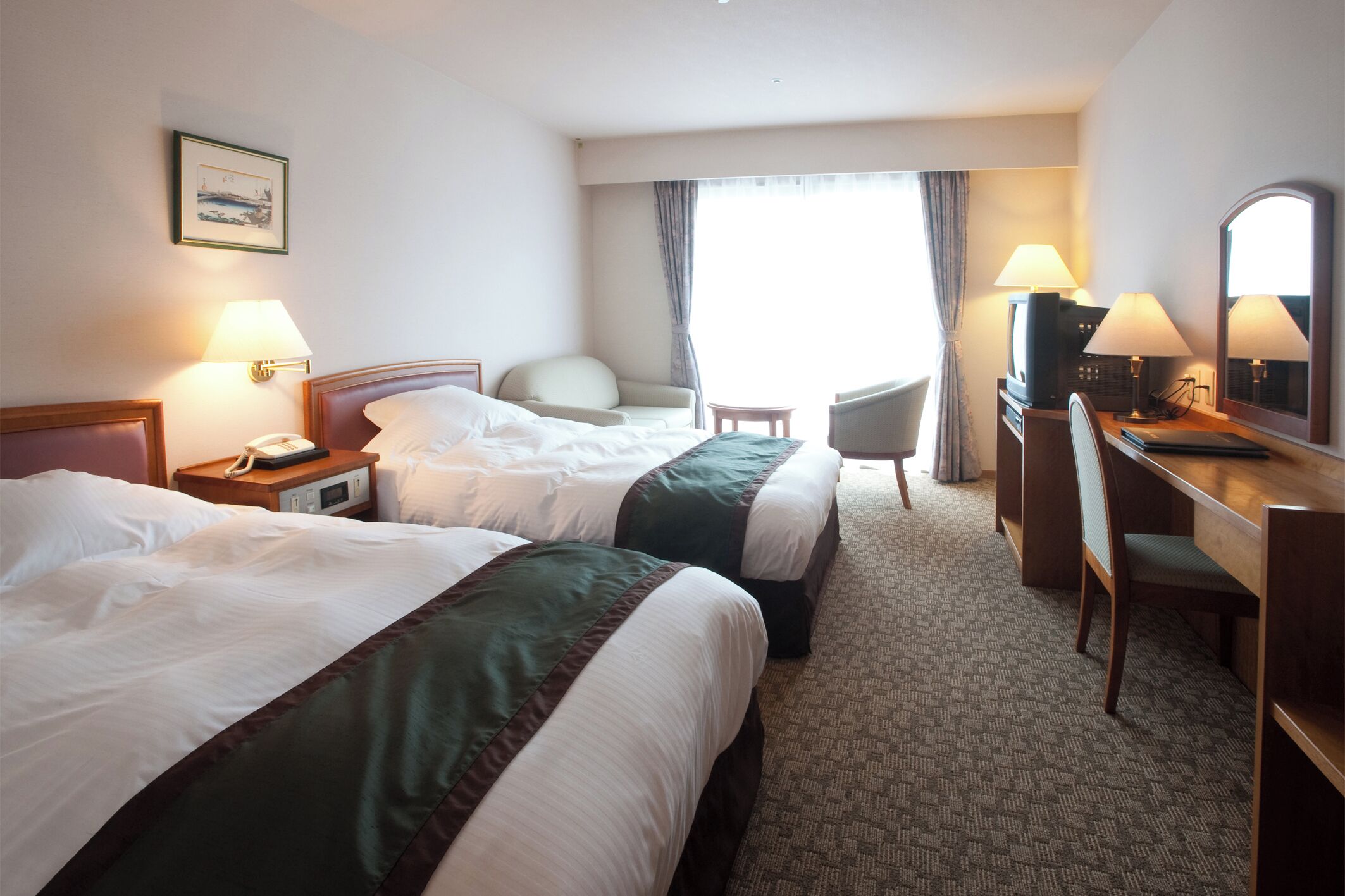 A hotel room with two beds, a desk, a chair, a TV, and a window with curtains.