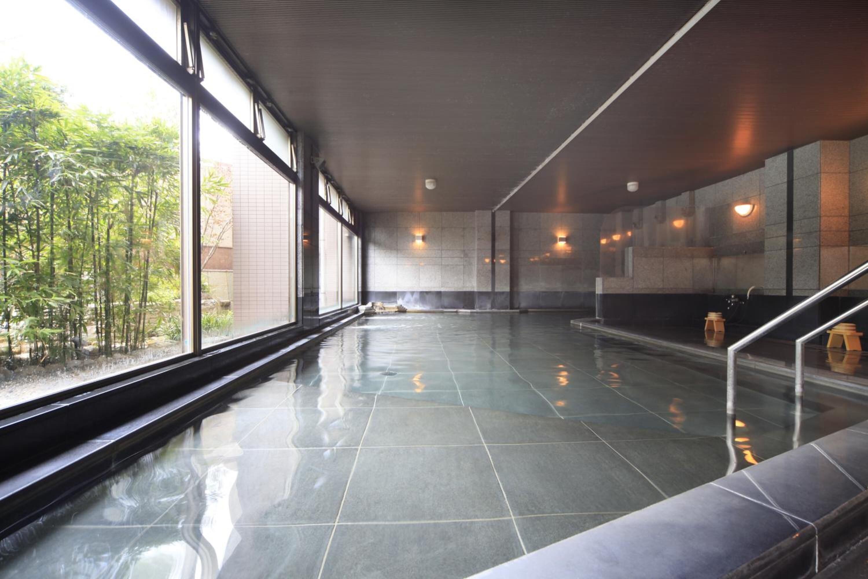 A spacious indoor area with a reflective floor, large windows, and a view of greenery outside.