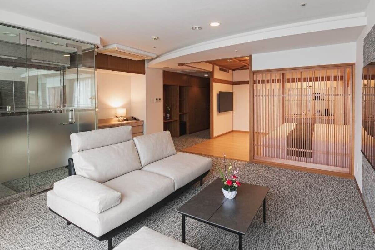 A modern living room with a sofa, a coffee table, and a glass partition.