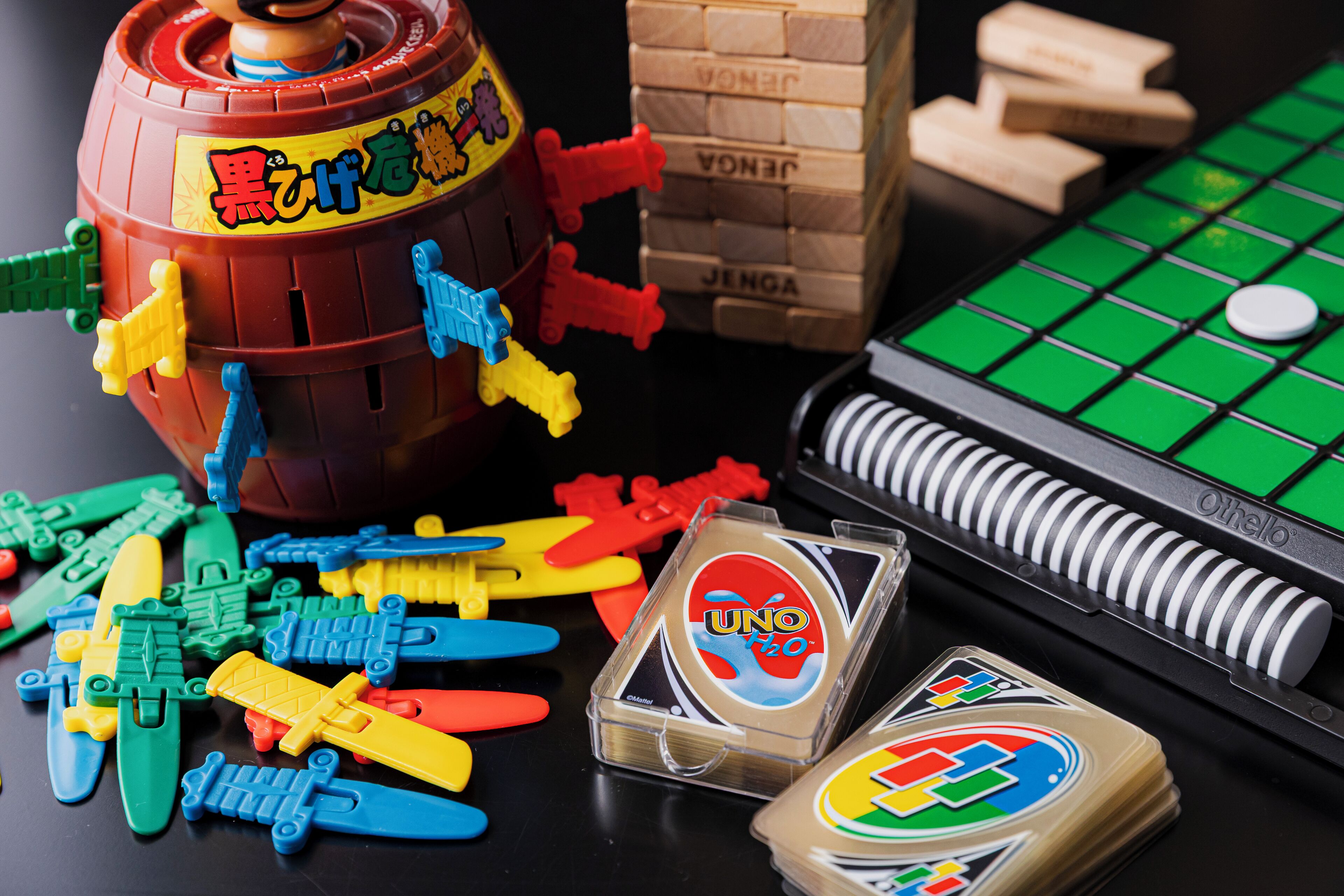 Ein Brettspielaufbau mit UNO-Karten, einer tonnenförmigen Spielfigur und bunten Plastikstücken.