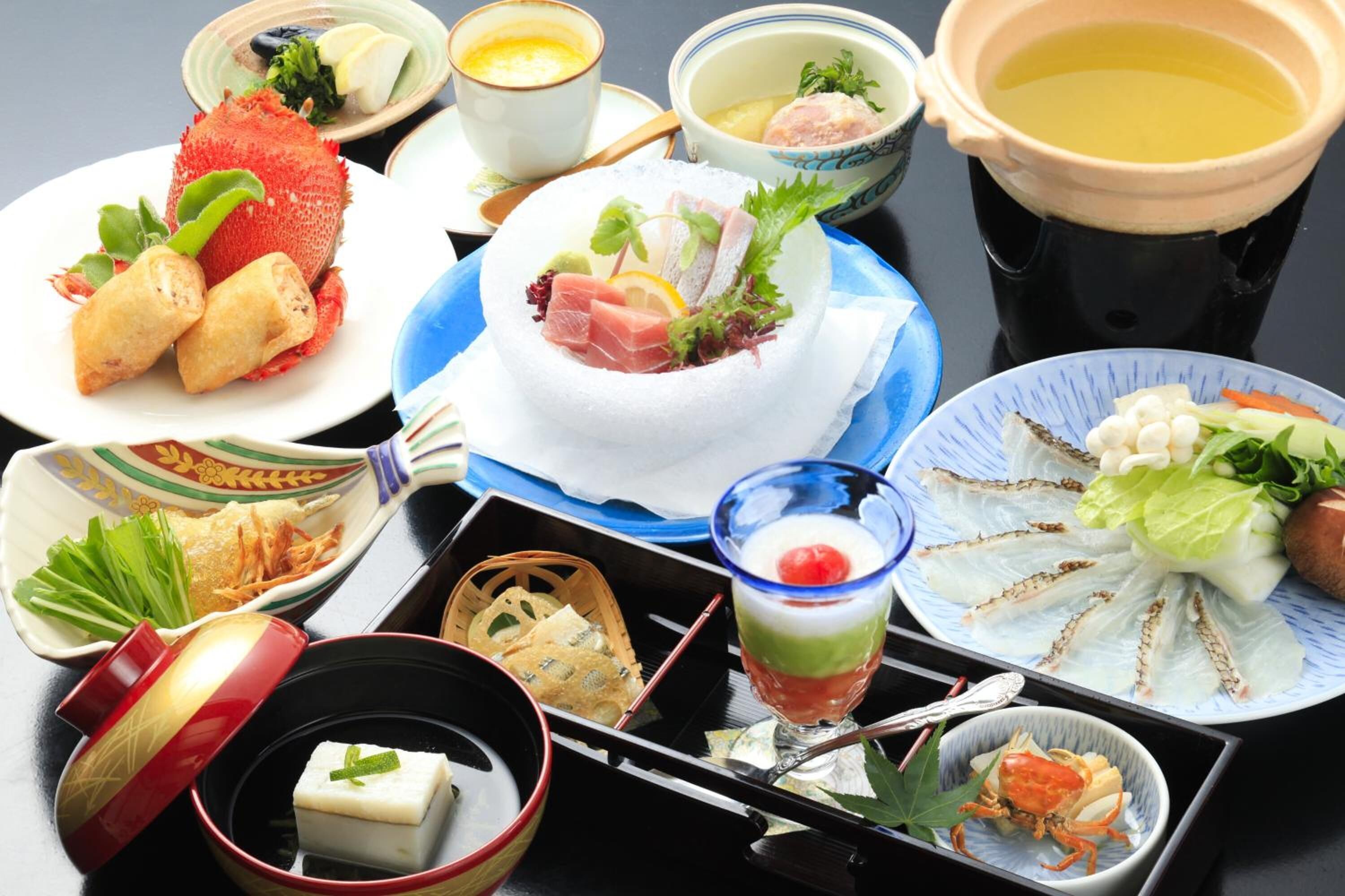 A variety of Japanese dishes including sushi, sashimi, and a bowl of soup, arranged on a table.