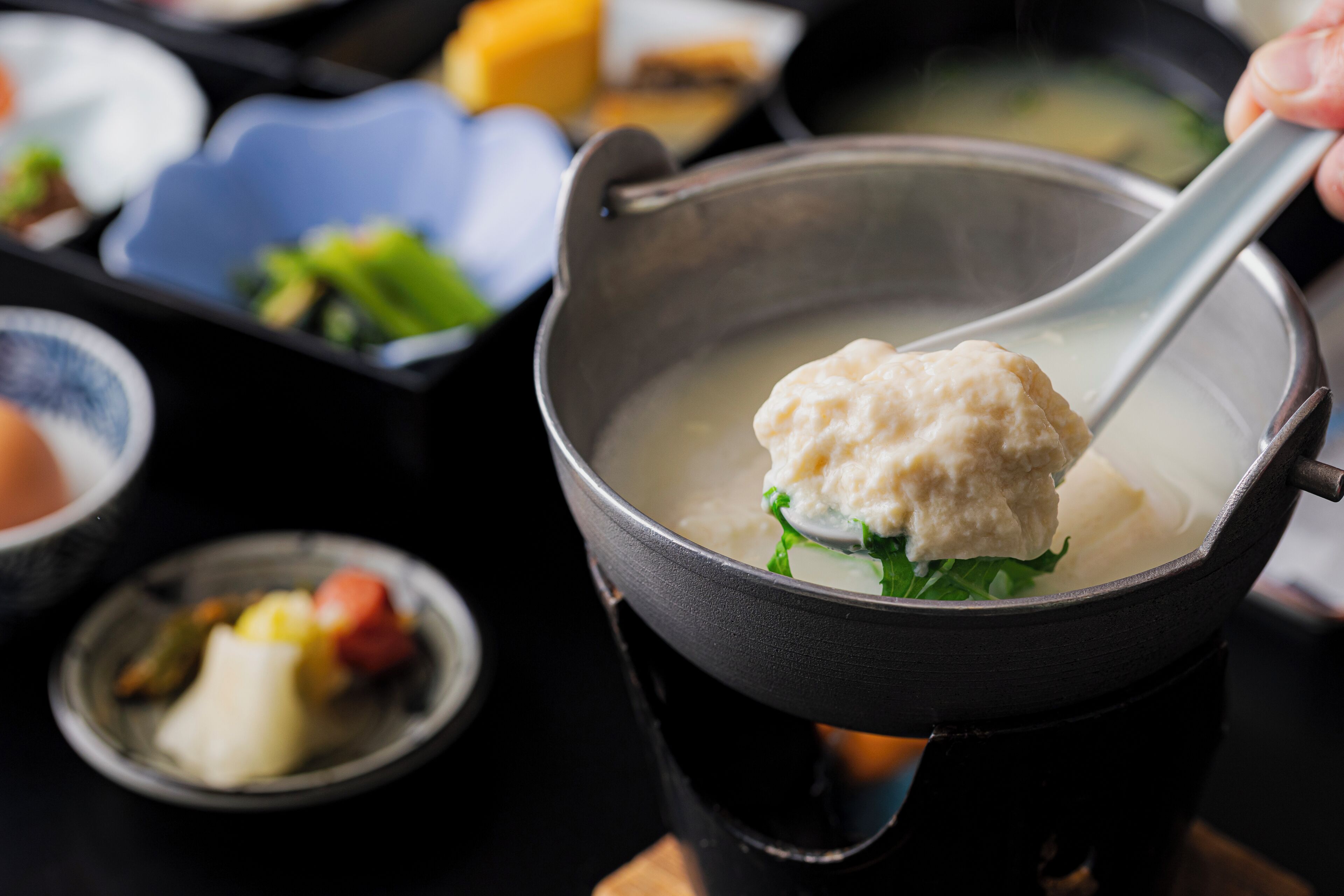 A hot pot with a dumpling and vegetables, surrounded by various dishes.