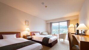 Habitación de hotel con dos camas, un escritorio, una silla y vistas a las montañas.