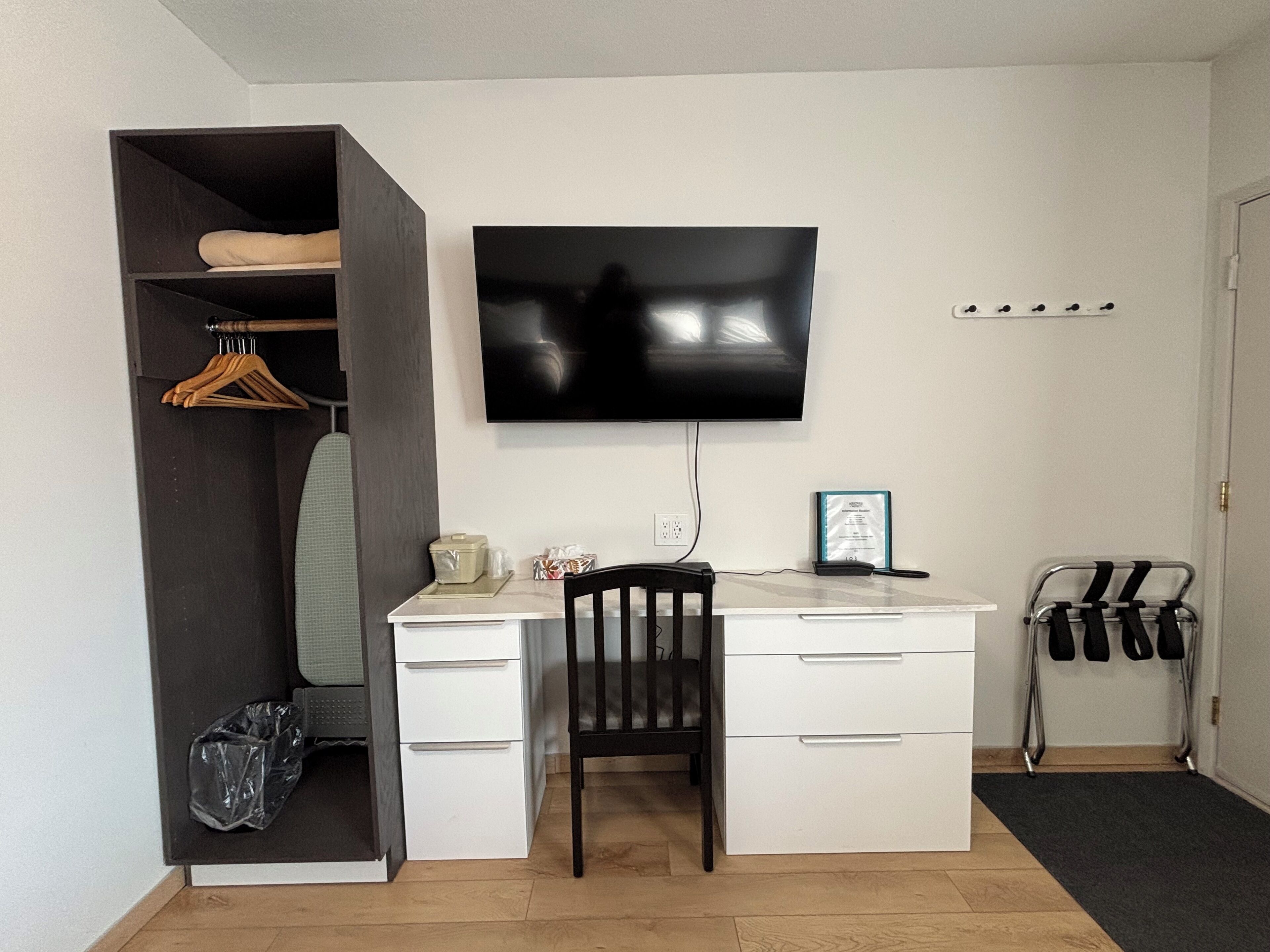 A compact room with a desk, chair, and a TV mounted on the wall.